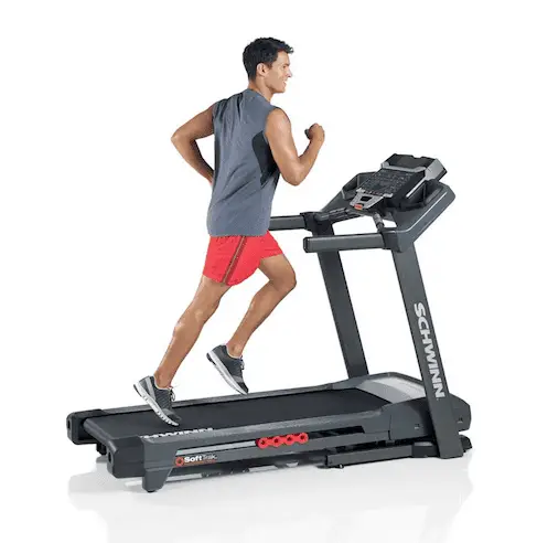 Man wearing gray sleeveless shirt and red pants running in a Schwinn 830 Treadmill