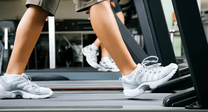 Leg wearing a white shoes and running in a treadmill
