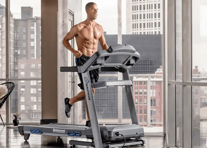 Shirtless man in black shorts running in a treadmill