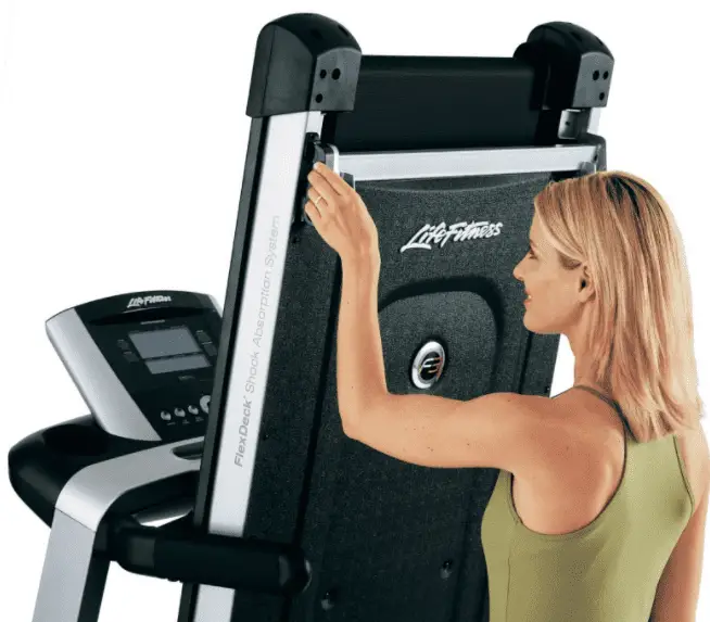 Woman wearing a green top and touching the edge of a life fitness treadmill
