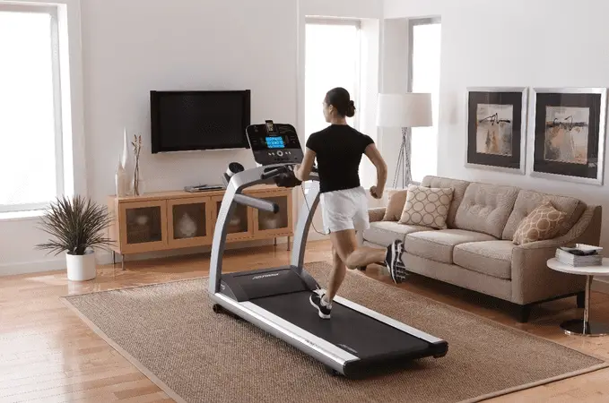 Woman in black top wearing a shorts and running on a treadmill inside a room